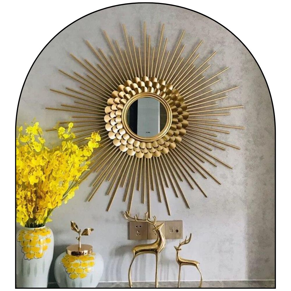 Decorative gold sunburst mirror on a wall with yellow flowers and decorative deer statues.
