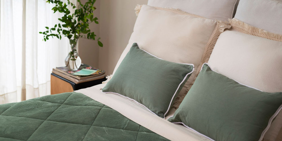Green bedding set on a bed with a nightstand and plant in the background